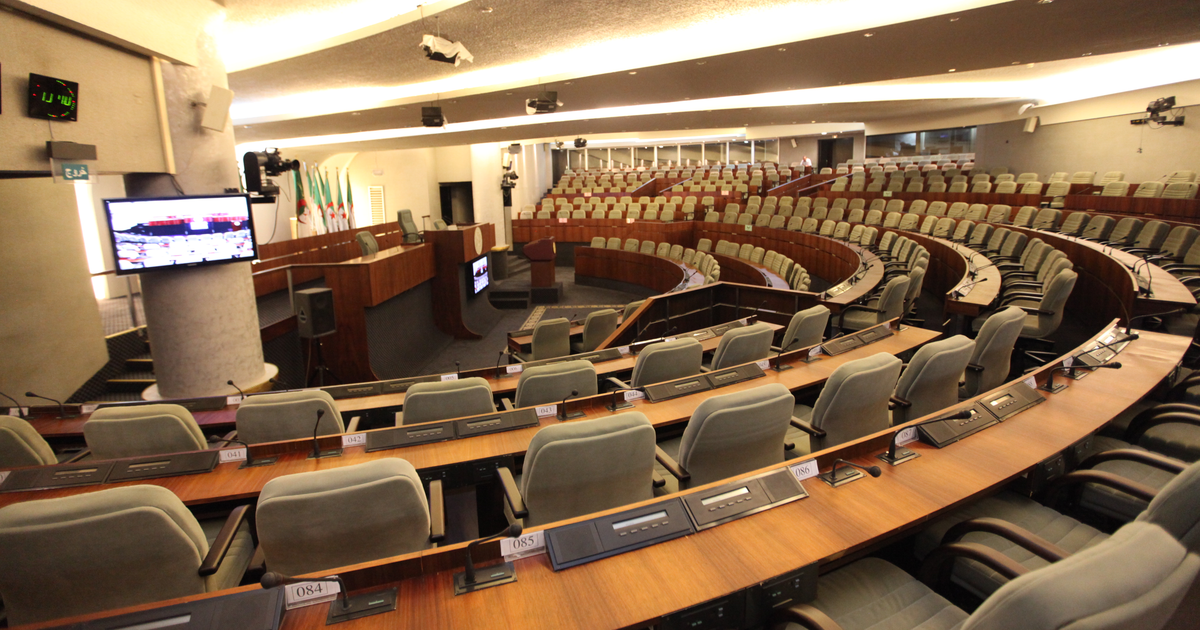 The empty chamber of Algeria's People's National Assembly in Algiers, with rows of seats and Algerian flags