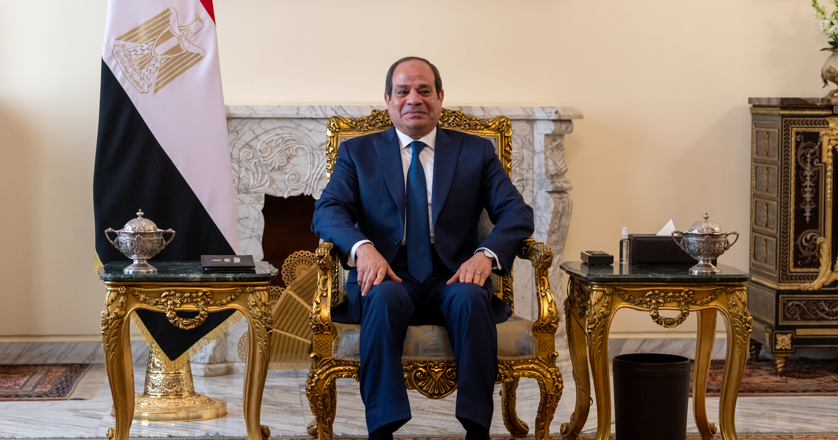 Abdel Fattah el-Sisi, in a dark suit, seated in a gilded chair beside an Egyptian flag.