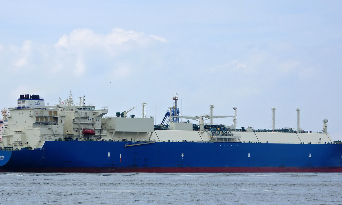The LNG carrier Maran Gas Mystras, with a dark blue hull, red waterline and white superstructure and cargo tanks, in the Nijlhaven at Europoort, Rotterdam, under a pale cloudy sky in July 2017.