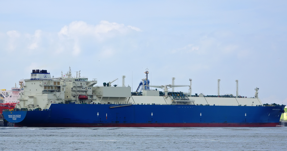 The LNG carrier Maran Gas Mystras, with a dark blue hull, red waterline and white superstructure and cargo tanks, in the Nijlhaven at Europoort, Rotterdam, under a pale cloudy sky in July 2017.
