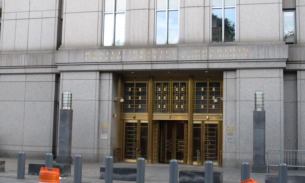 The granite entrance of a federal courthouse: gold lettering reading Daniel Patrick Moynihan United States Court House above bronze-framed glass doors, the number 500 beside them and steel bollards along the sidewalk.