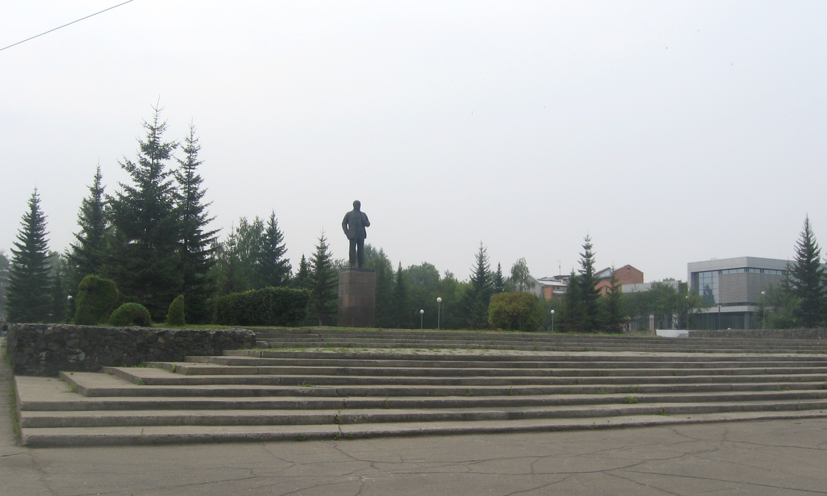 Lenin Square in Shelekhov, Irkutsk Oblast, under a pale sky in August 2013, with mid-rise apartment blocks and a paved plaza.