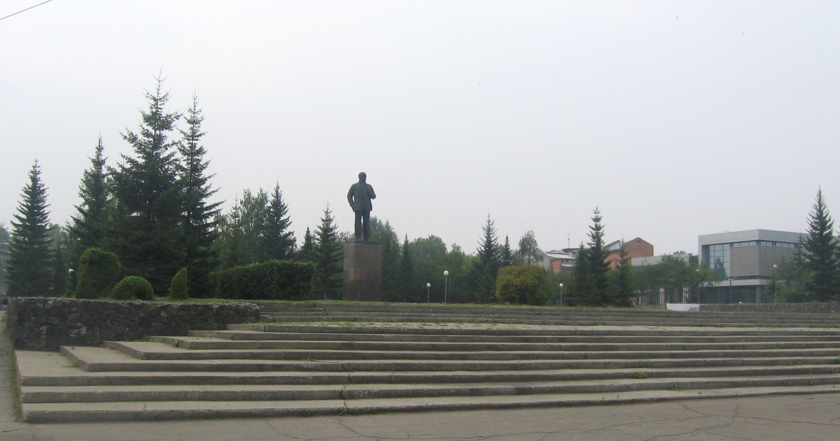 Lenin Square in Shelekhov, Irkutsk Oblast, under a pale sky in August 2013, with mid-rise apartment blocks and a paved plaza.