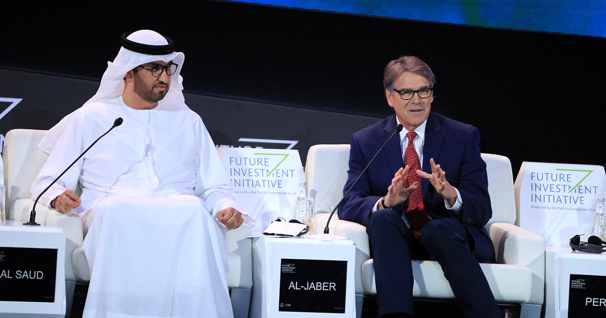 Two men seated in white armchairs on a conference stage, behind table cards reading "Future Investment Initiative", Riyadh, October 2019.